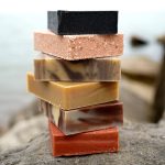 Ręce mieszające naturalne oleje z ługiem w przezroczystej misie na kuchennym blacie