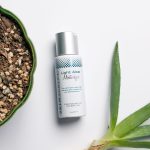 Elegancka szklana butelka domowego balsamu po goleniu stoi obok maszynki