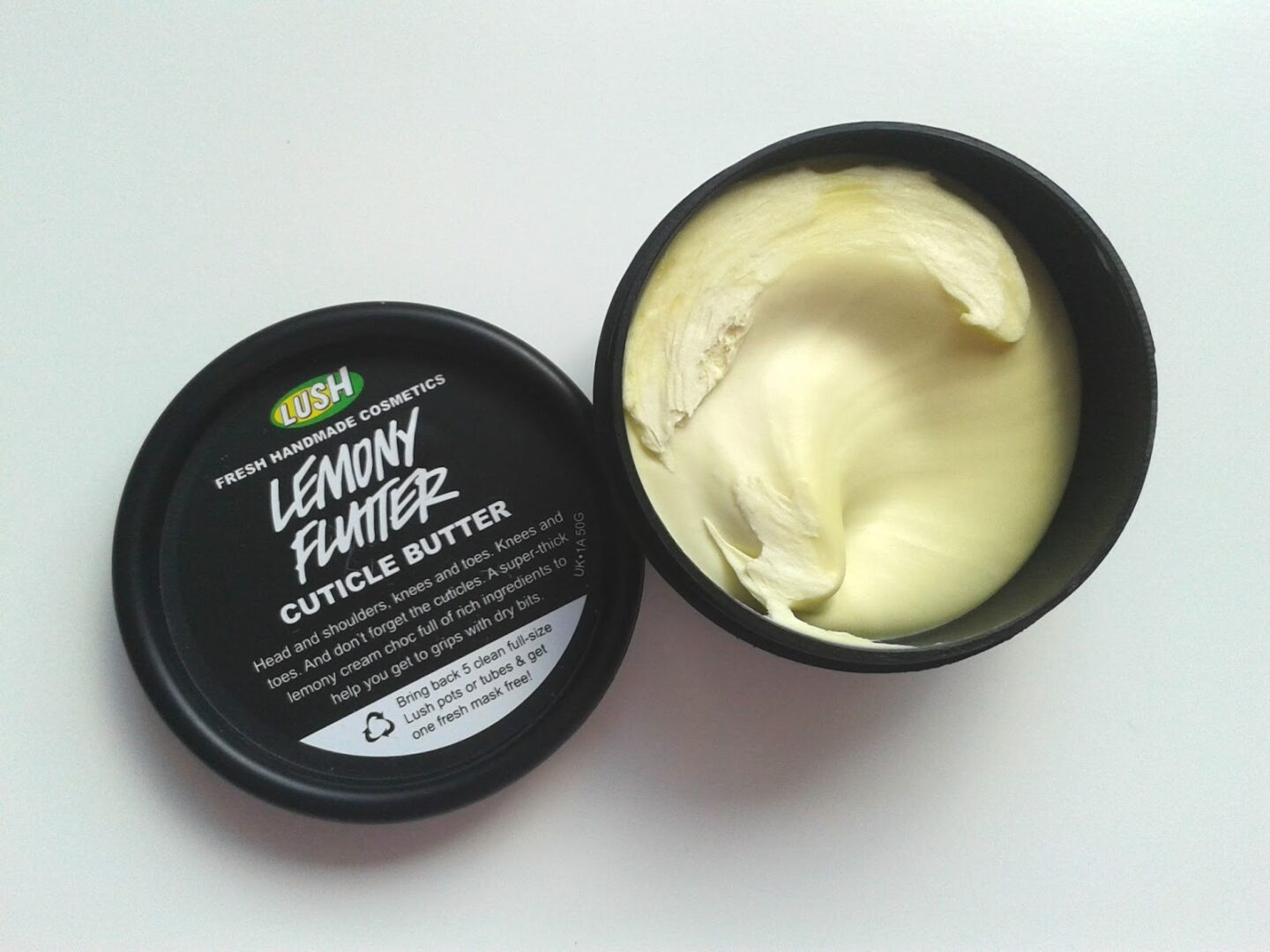 Elegancka buteleczka balsamu do skórek stoi wśród zadbanych paznokci z czerwonym lakierem