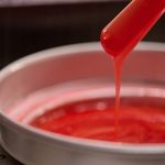 młoda kobieta prezentująca gładkie nogi obok słoików wosku i pasty cukrowej