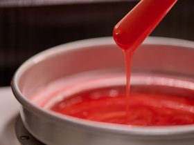 młoda kobieta prezentująca gładkie nogi obok słoików wosku i pasty cukrowej