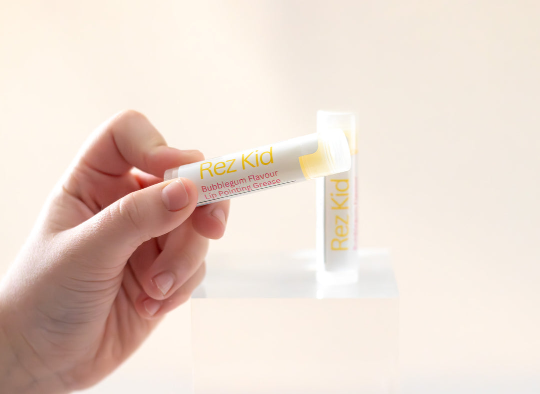 dziecko trzyma tubkę balsamu do ust małe rączki dziecka trzymają tubkę balsamu z owocową etykietą na stole