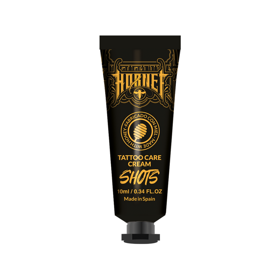 Ręka w rękawiczce delikatnie nakłada biały krem na czerwony świeży tatuaż na przedramieniu