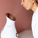 kobieta siedzi przed sauną jonową do twarzy z unoszącą się parą