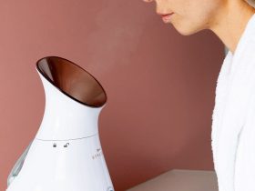 kobieta siedzi przed sauną jonową do twarzy z unoszącą się parą