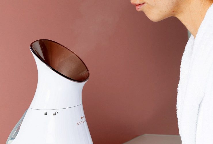 kobieta siedzi przed sauną jonową do twarzy z unoszącą się parą