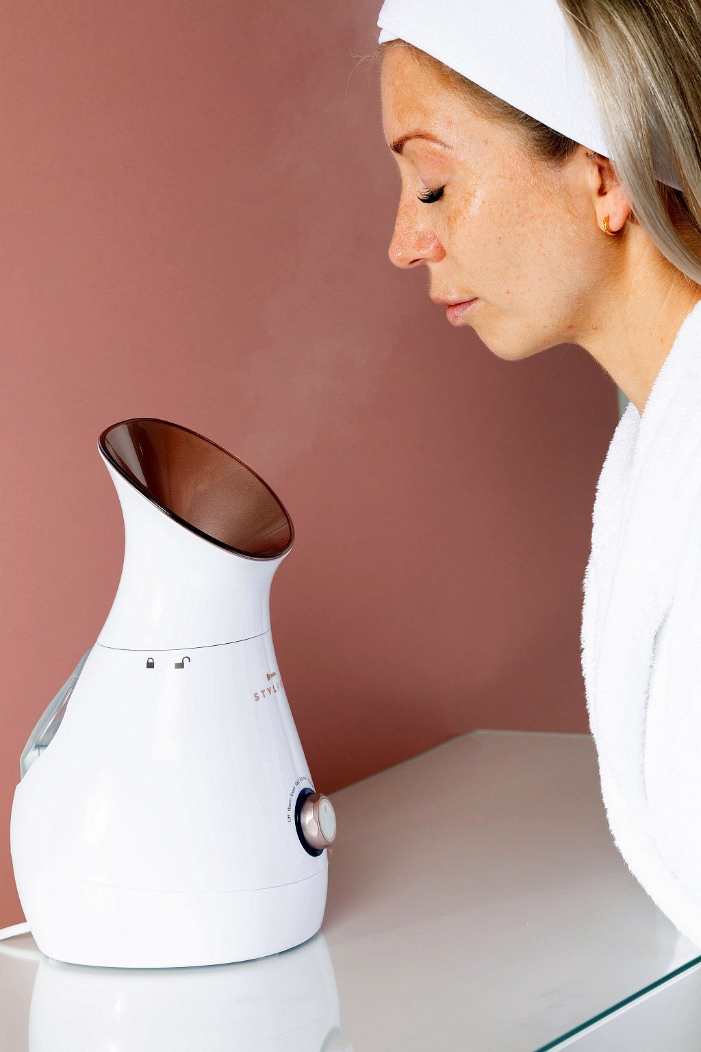 kobieta siedzi przed sauną jonową do twarzy z unoszącą się parą