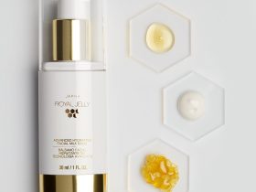 białe mleczko balsamiczne w przezroczystej butelce na tle gładkiej skóry ręki