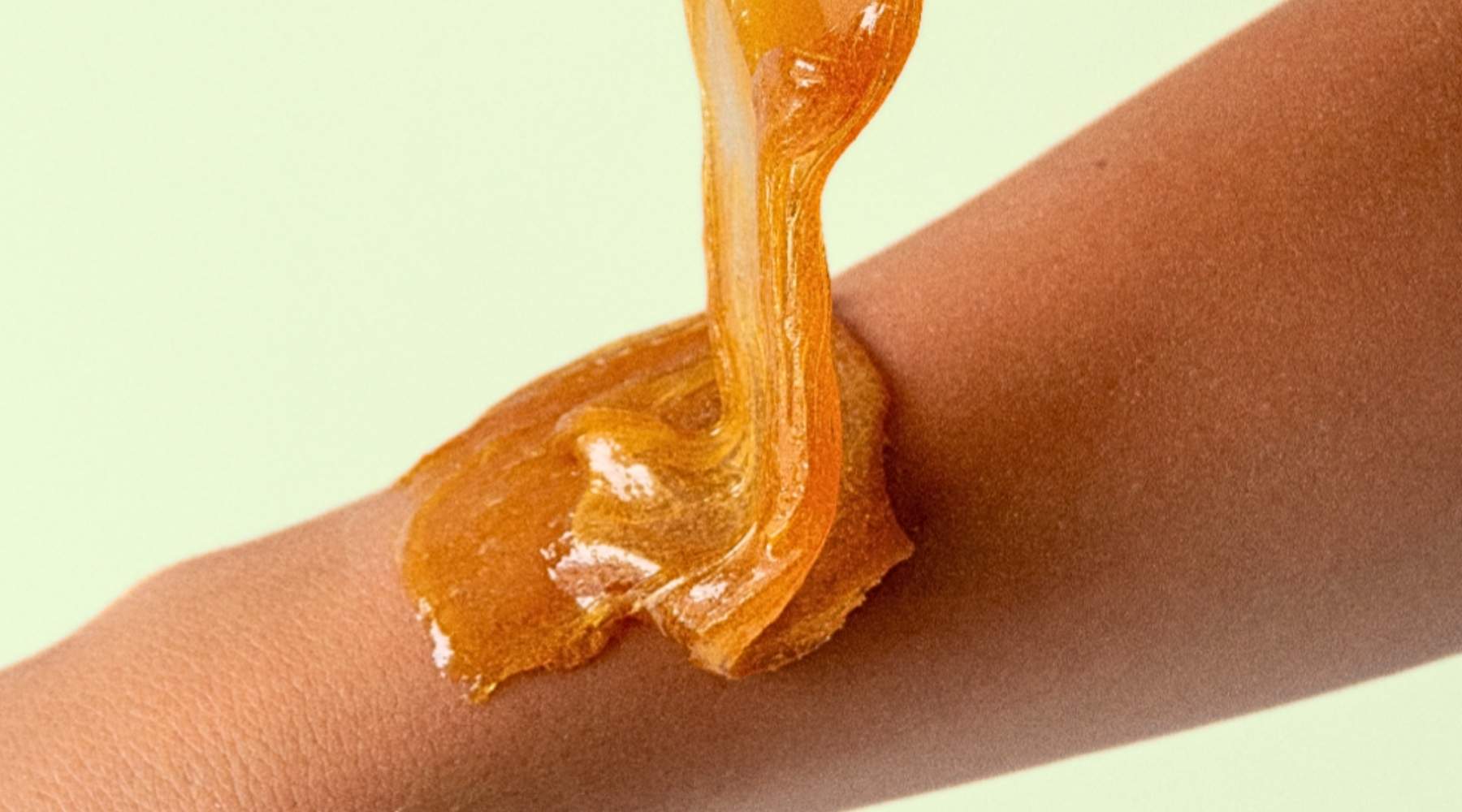 aplikacja wosku na nogę kosmetyczka nakładająca ciepły wosk szpatułką na udo klientki